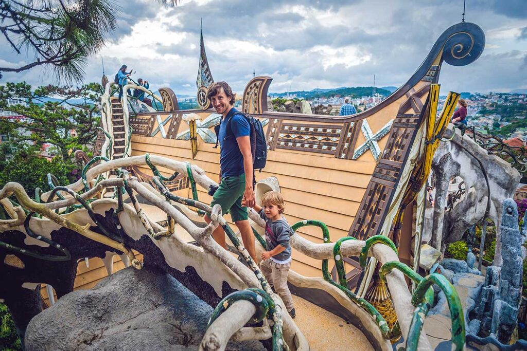 A father and young boy climb the curving sculpted walkways of the Crazy House in Dalat, one of the more playful stops when visiting Vietnam with kids.