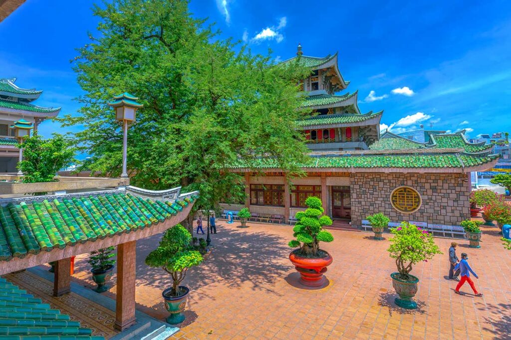 Courtyard of Ba Chua Xu Temple on Sam Mountain, showing traditional architecture, bonsai trees, and tiled roofs.