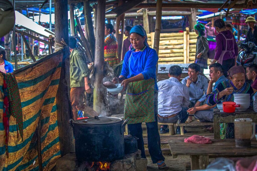 A local ethnic woman is cooking food at the Bac Ha Market