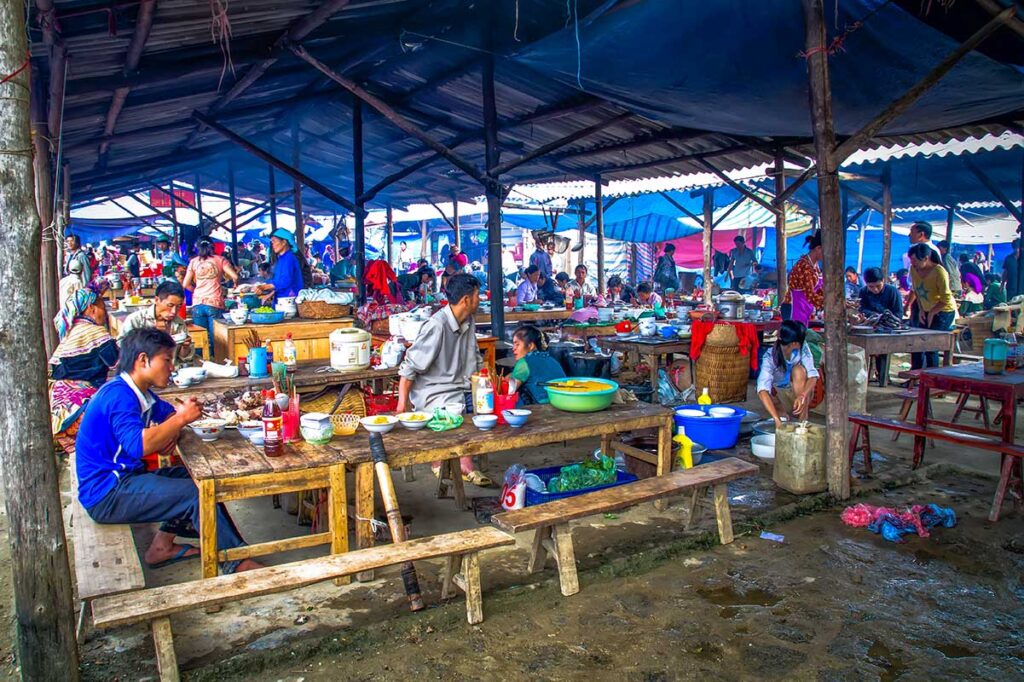 A covered area of Bac Ha Market with tables and benches where ethnic minorities eat locally made street food dishes