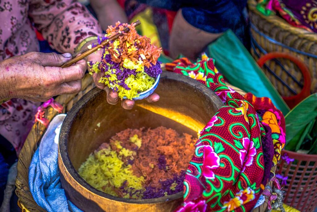 An ethnic woman on Bac Ha Market is holding a dish made out of different colored rice