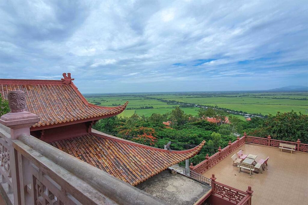 View from Sam Mountain in Chau Doc with temple roof and panoramic rice fields of An Giang Province.