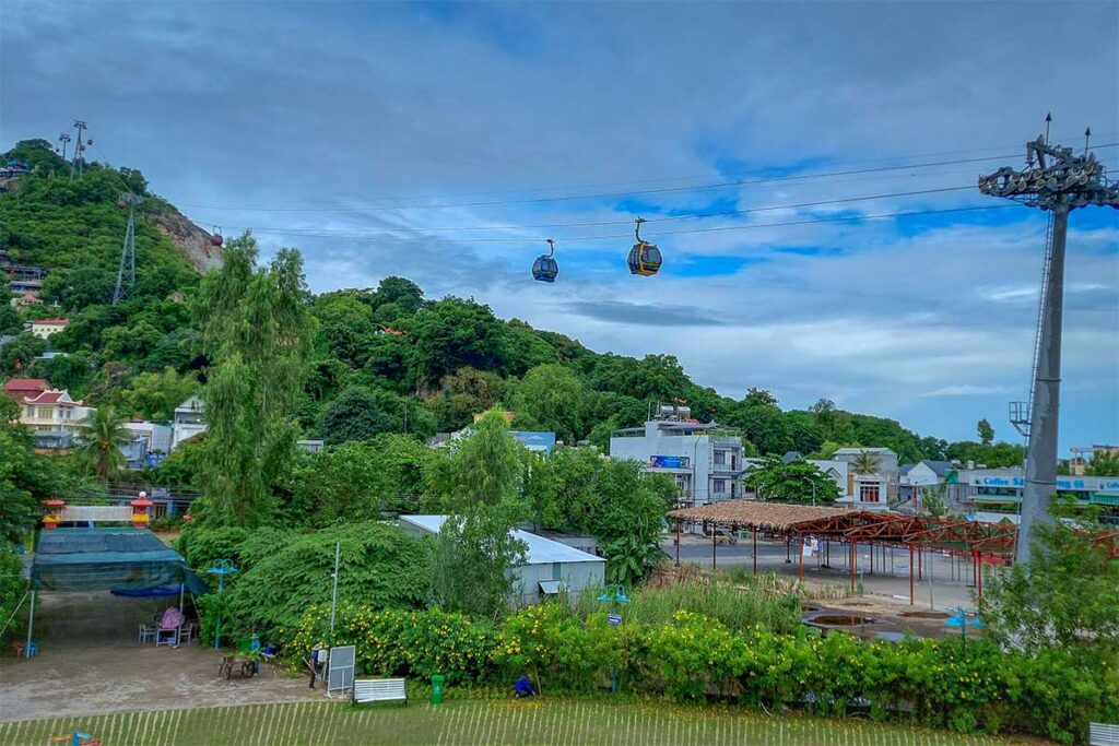 Cable cars running up Sam Mountain in Chau Doc, An Giang, with green hills and town below.