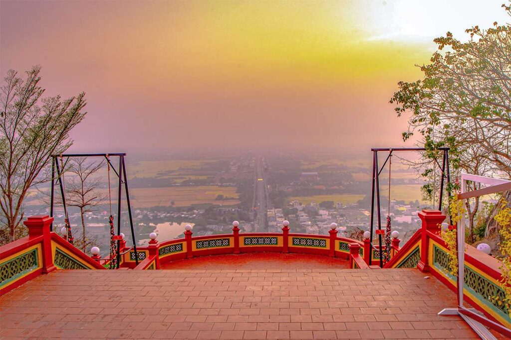 Scenic view from the summit of Sam Mountain in Chau Doc at sunset, overlooking rice fields and Chau Doc town.