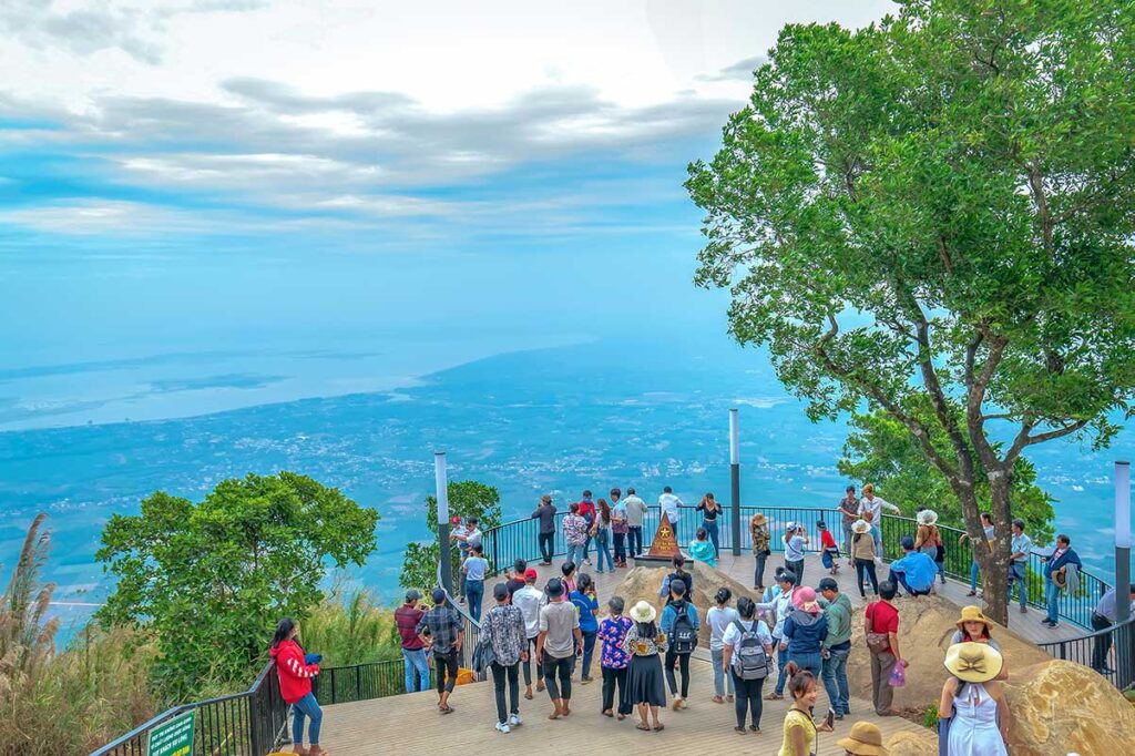 People looking at the view from the peak of Ba Den Mountain (Black Virgin Mountain) over the surrounding flat landscape