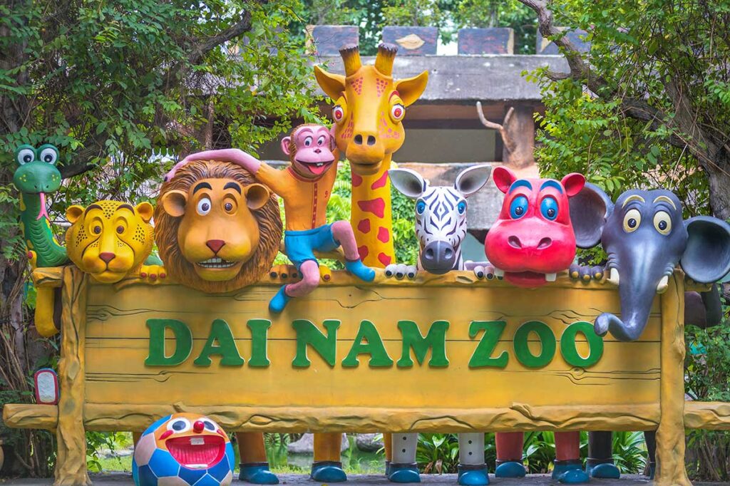 A colorful sign with faces of animals that says " Dai Nam Zoo" 