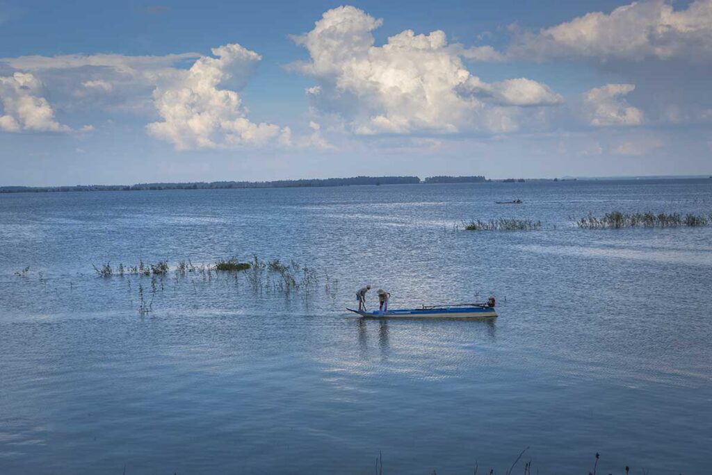 Two fisherman on a small wooden boat on Dau Tieng Lake in Tay Ninh