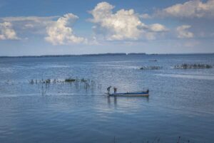 Two fisherman on a small wooden boat on Dau Tieng Lake in Tay Ninh