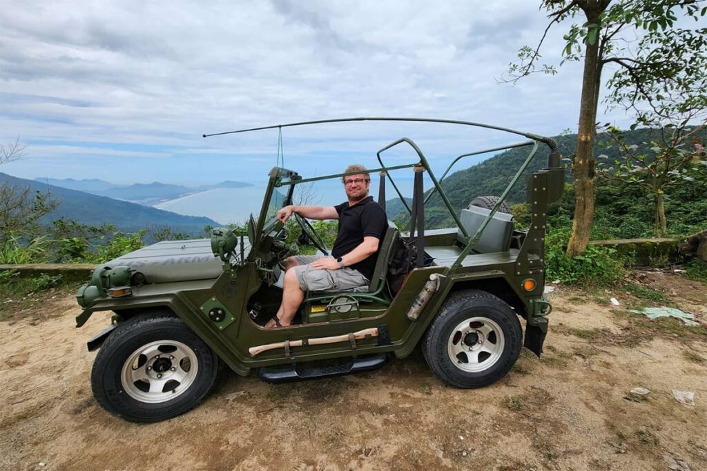 A tourist sitting in a military open jeep on the Hai Van pass that is part of a tour between Hoi An and Hue