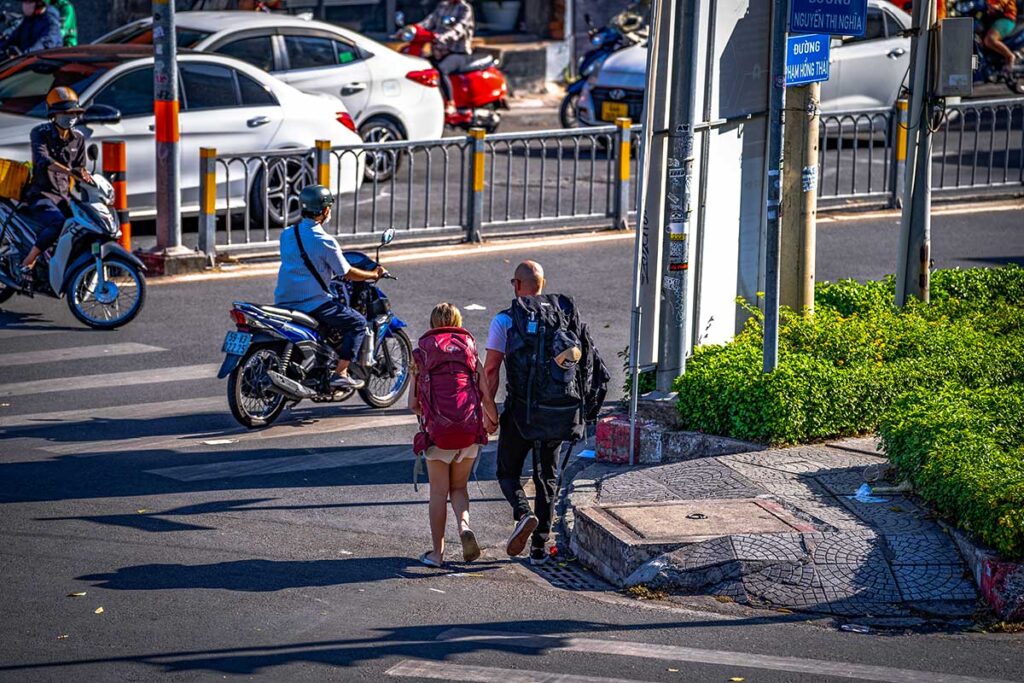 Two backpackers navigating a busy street while crossing the road in Vietnam.