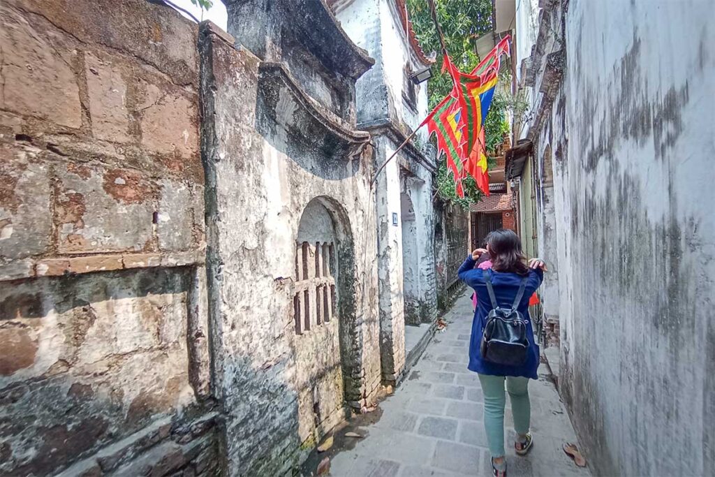 tourists walking through a narrow old street of Bat Trang Pottery Village