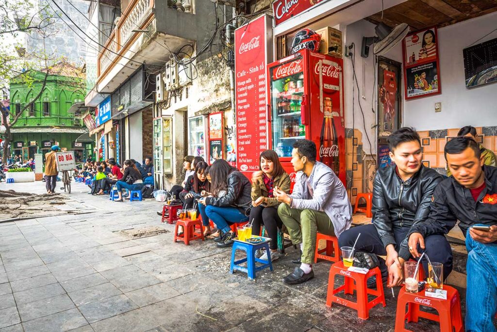 Local Street Coffee Scene in Hanoi: Locals enjoy their morning coffee on colorful plastic stools at a traditional street-side cafe in Hanoi.