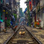 Hanoi Train Street: A train rumbles through the narrow Hanoi Train Street, passing between vibrantly colored houses.