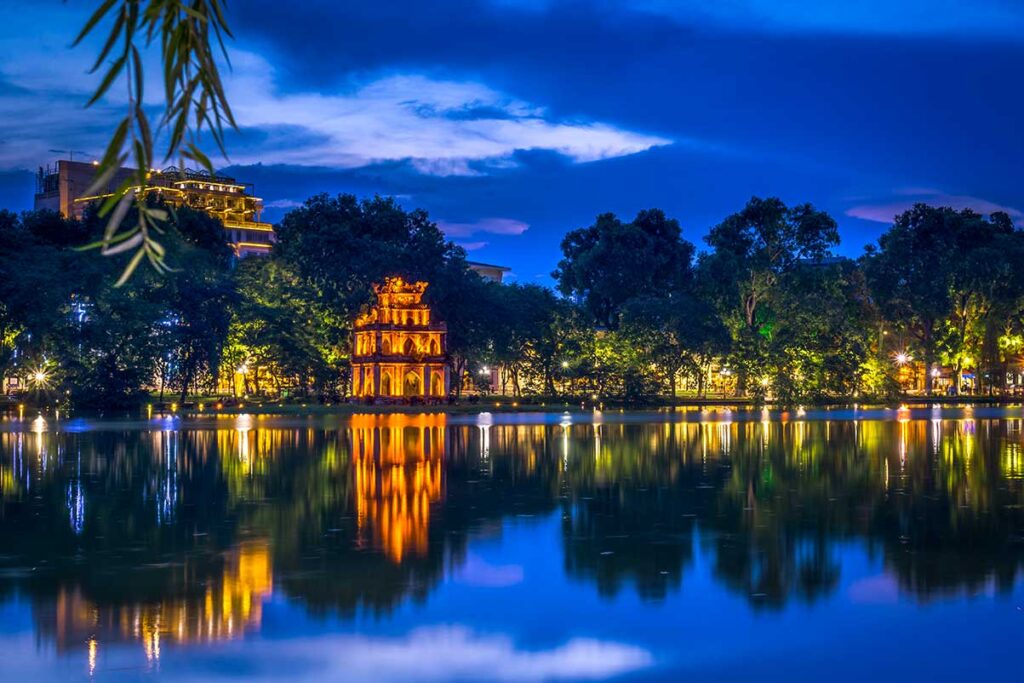 Hoan Kiem Lake at Night: The illuminated Turtle Tower shimmers on the calm waters of Hoan Kiem Lake in Hanoi, a popular nighttime photography spot. (best Instagram spots in Hanoi)