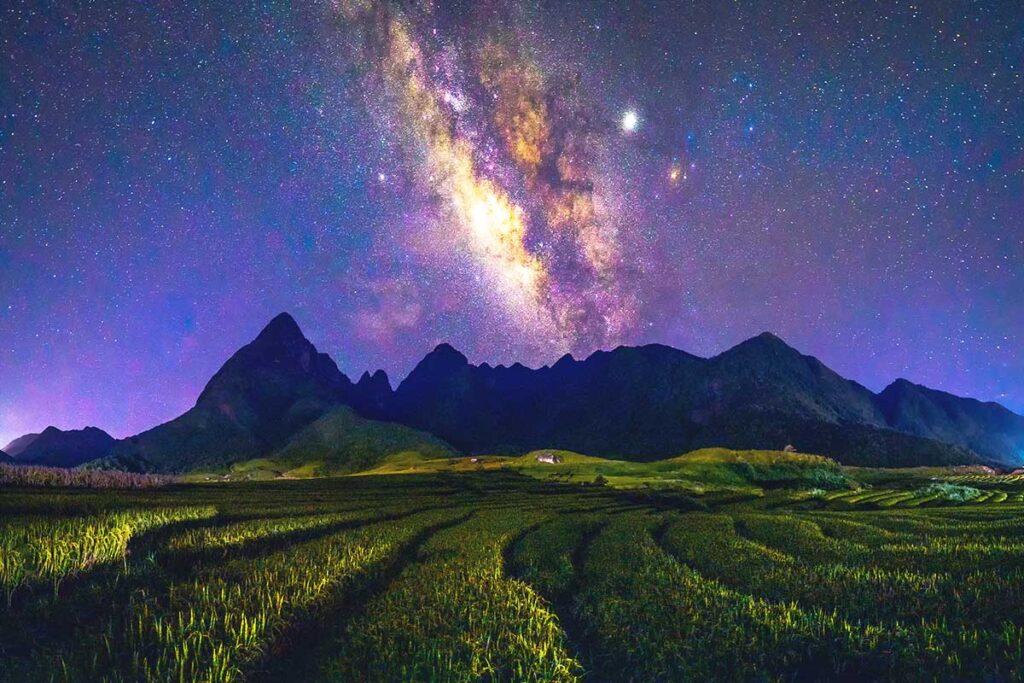 stunning night time with Milky Way visible above rice fields and Fansipan mountain at Sapa