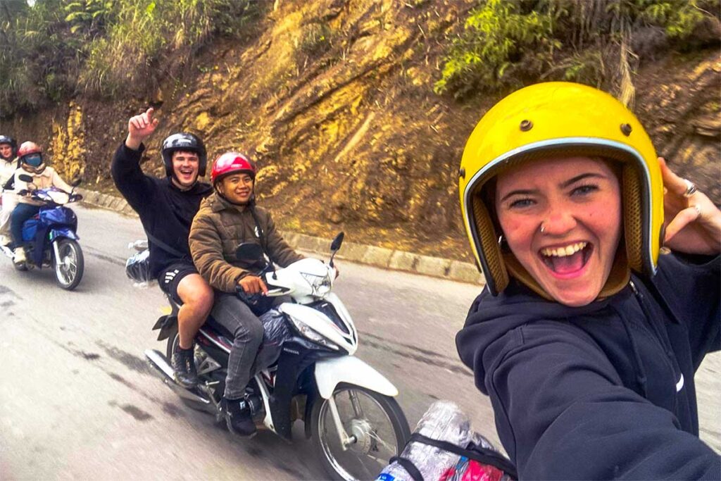 Sapa motorbike tour with two foreign tourist on the back of a motorbike with local guide