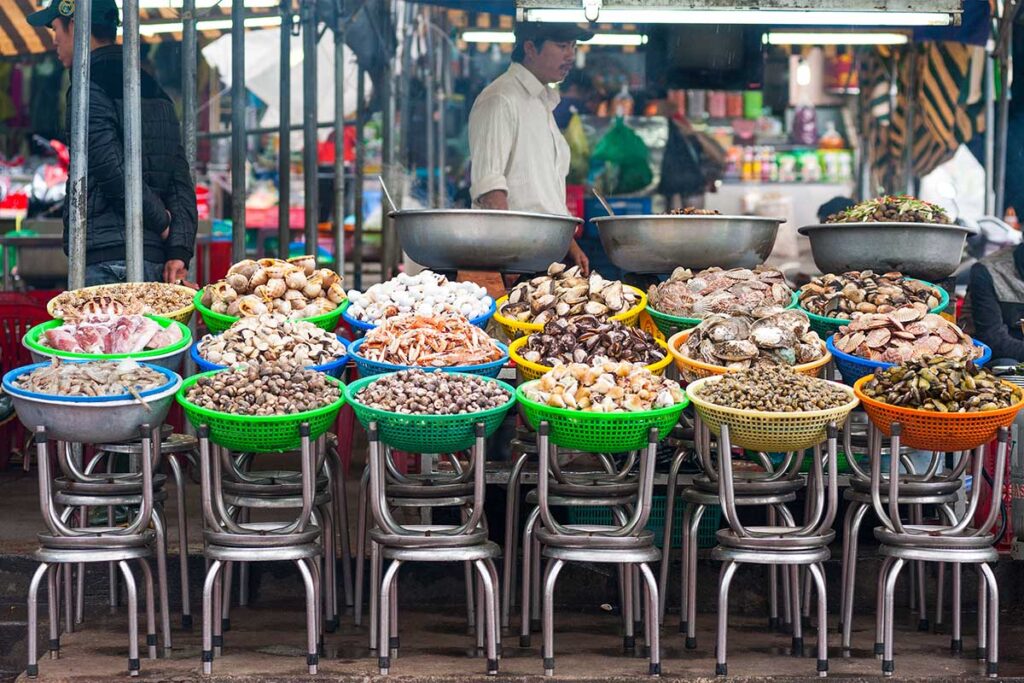 Vietnamese market showcasing multiple baskets filled with various shellfish, a common allergen.