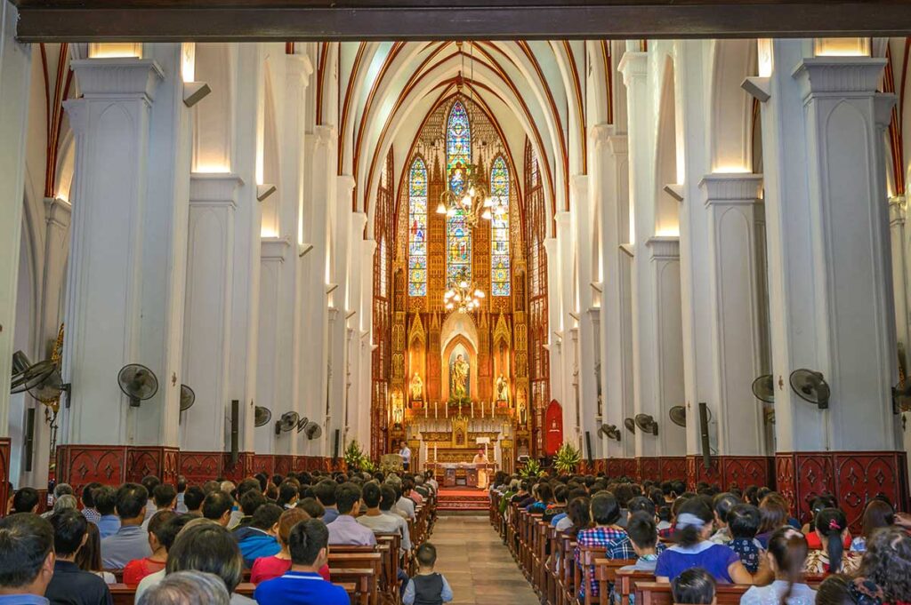 St. Joseph's Cathedral Interior During Mass: Worshippers gather for mass inside St. Joseph's Cathedral in Hanoi, listening to the Archbishop's sermon.