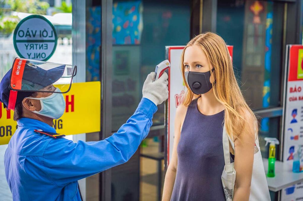 Tourist woman having her temperature checked in Vietnam, emphasizing health and safety measures during travel.