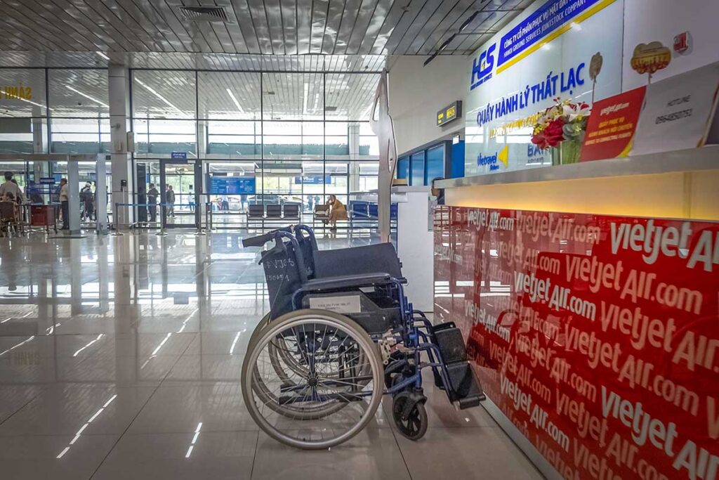 Empty wheelchair at VietJet Air service desk in a Vietnamese airport, highlighting accessibility services for travelers with disabilities.