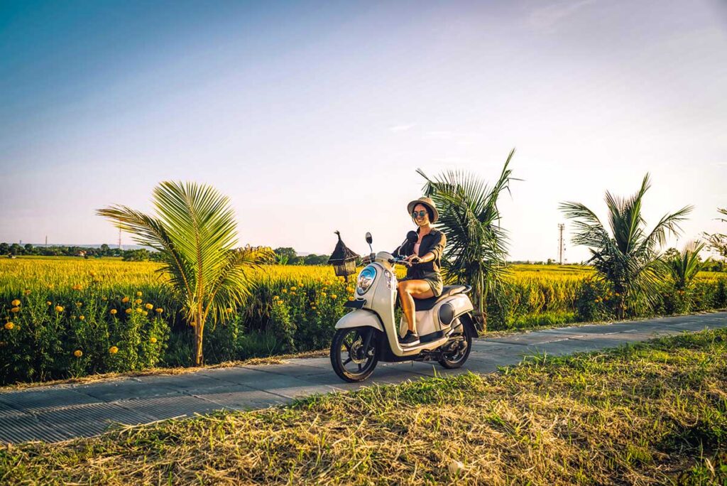 Female solo traveler riding a scooter through the picturesque rice fields of Vietnam.