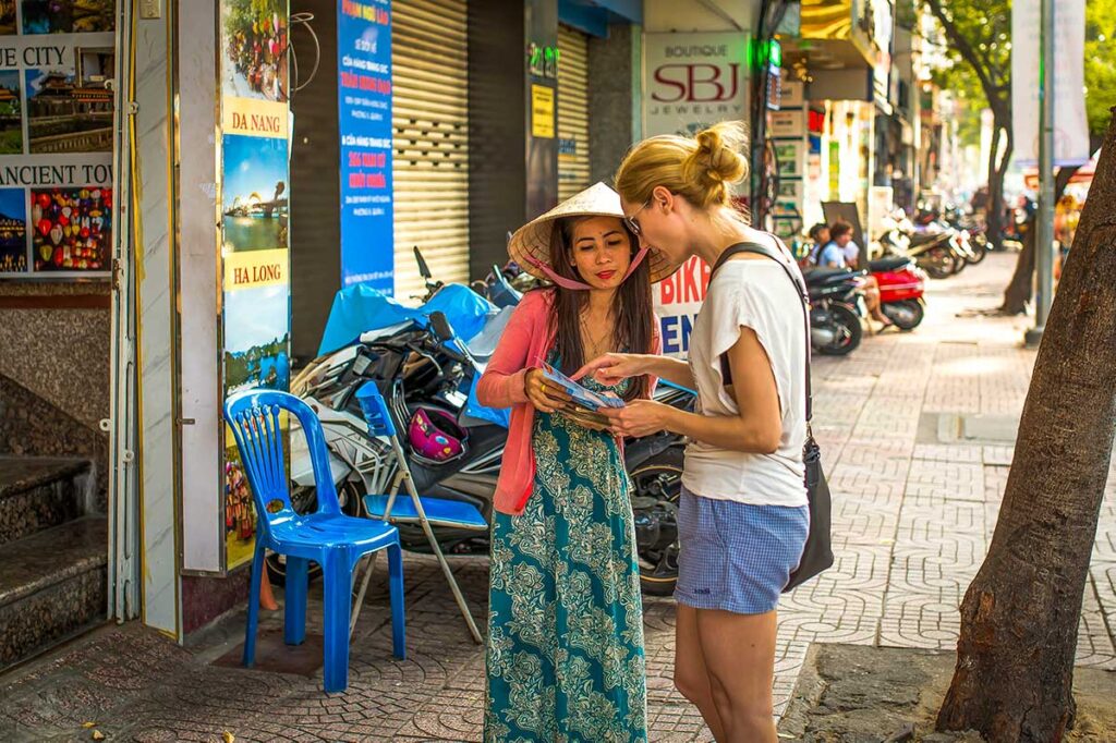 Solo female traveler in Vietnam asking for directions from a local Vietnamese woman on the street.