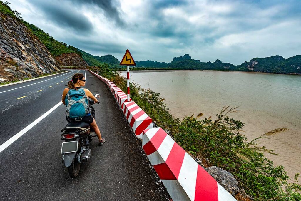 A tourist driving a motorbike along the coast of Cat Ba Island