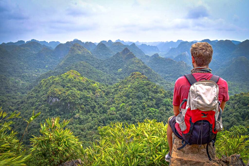 A tourist sitting at a viewpoint in Cat Ba National Park that you can reach by trekking