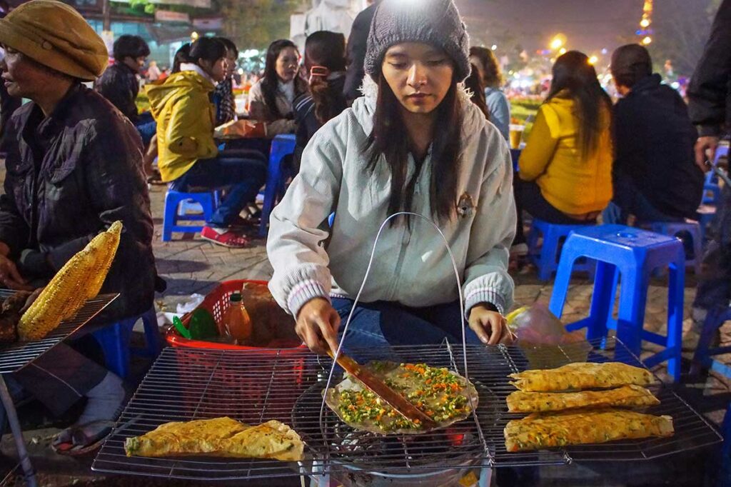 A local girl girl grilling rice paper pizza on the Dalat Night Market