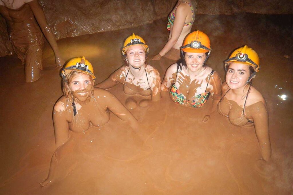 A group of travelers bathing in a mud bath inside the Dark Cave in Phong Nha