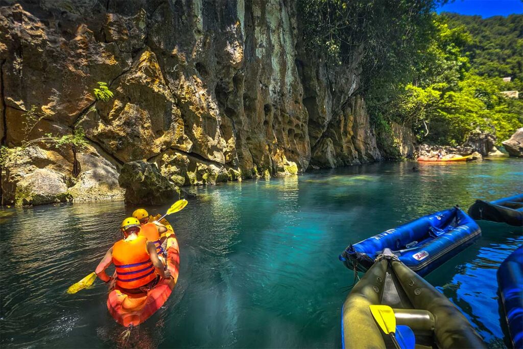 Two travelers are kayaking on the river at entrance of Dark Cave in Phong Nha