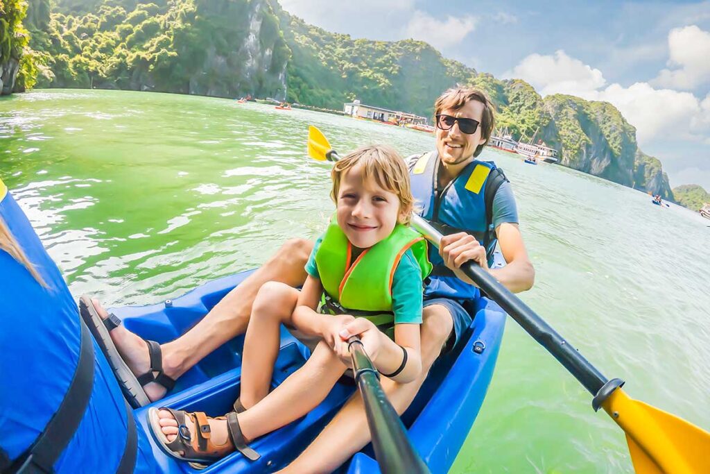 A man and his son are kayaking in Halong Bay