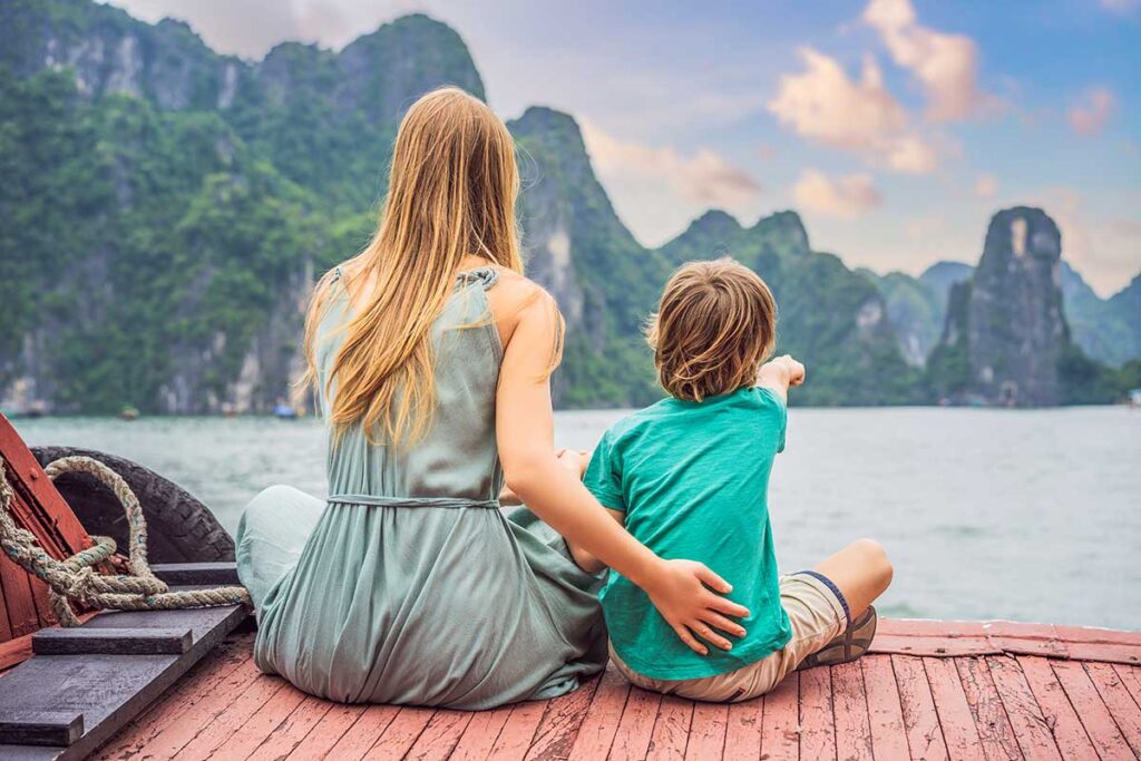 A kid and his mother sitting on the back of a cruise boat through Halong Bay