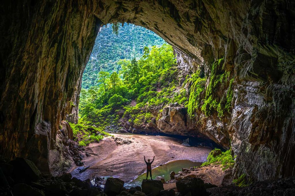 A huge cave opening with jungle inside and small river at Hang En Cave, Phong Nha, Vietnam