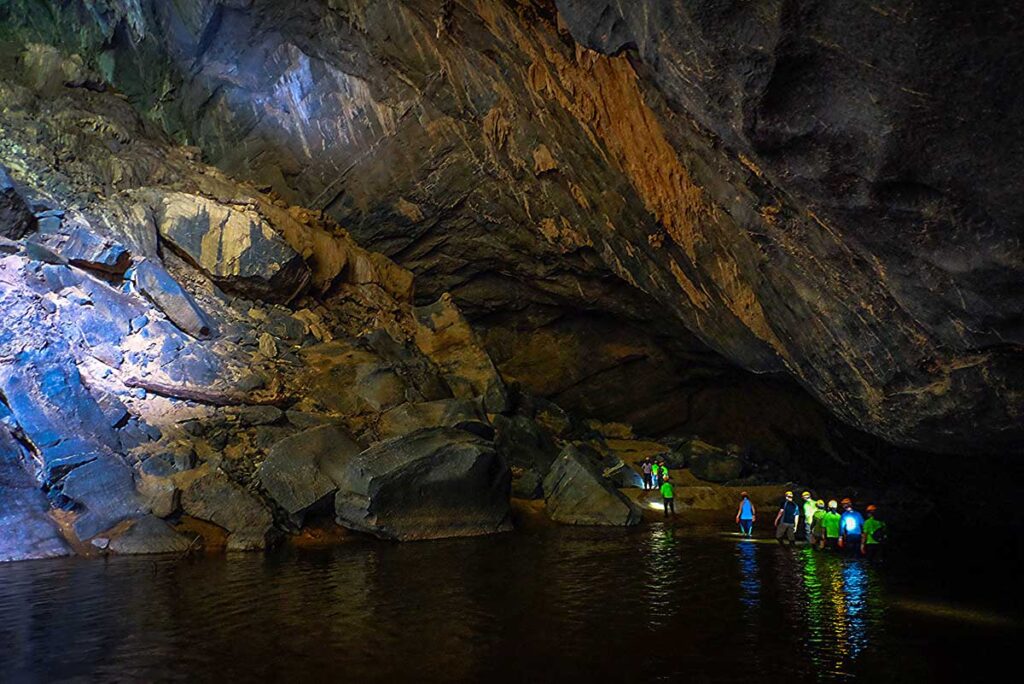 A group of travelers caving through the underground river of Hang En Cave in Phong Nha