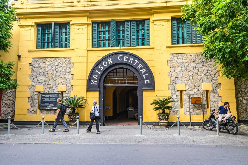 Hoa Lo Prison museum front the outside with yellow walls and a sign above the door