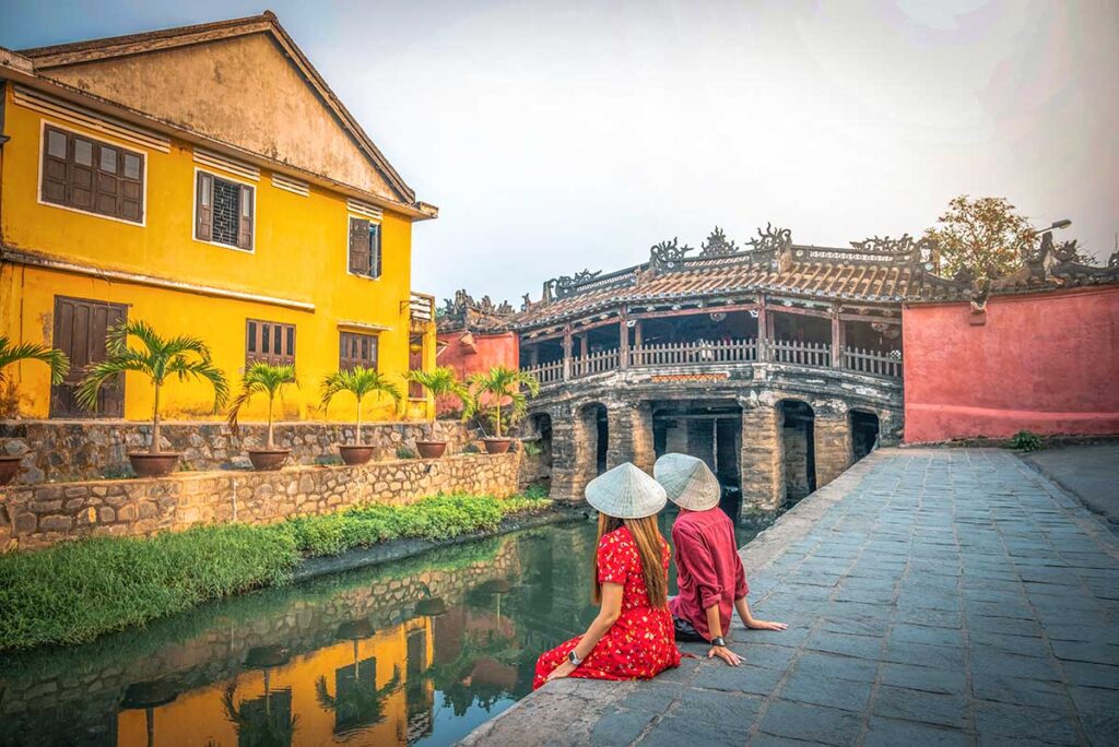 A couple sitting next to the Japanese Bridge in Hoi An for a romantic time in Vietnam