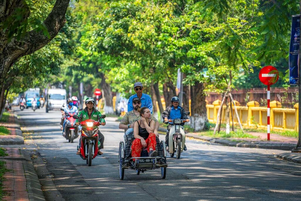 A couple sitting together on a cyclo while riding through Hue