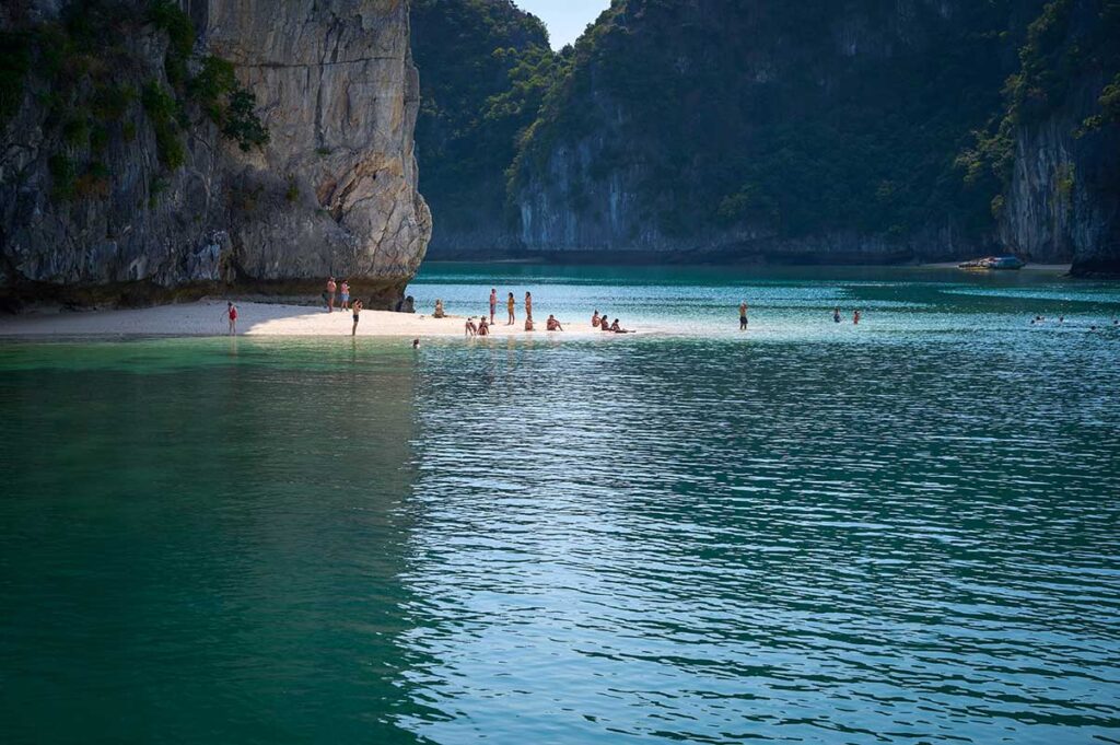 A group of travelers relaxing on a small beach in Lan Ha Bay