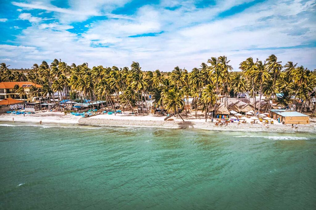 The view of palm trees, white sand, clear ocean water of Mui Ne beach town in Vietnam