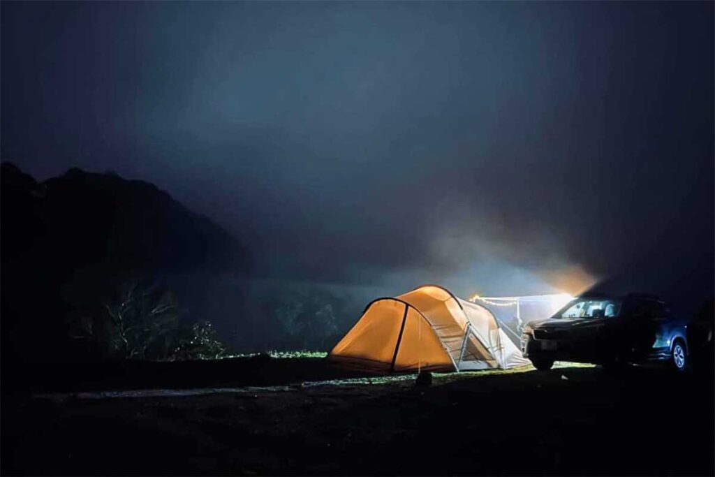 A dark Phia Oac National Park at night with only lights coming from a tent of people camping inside the national park