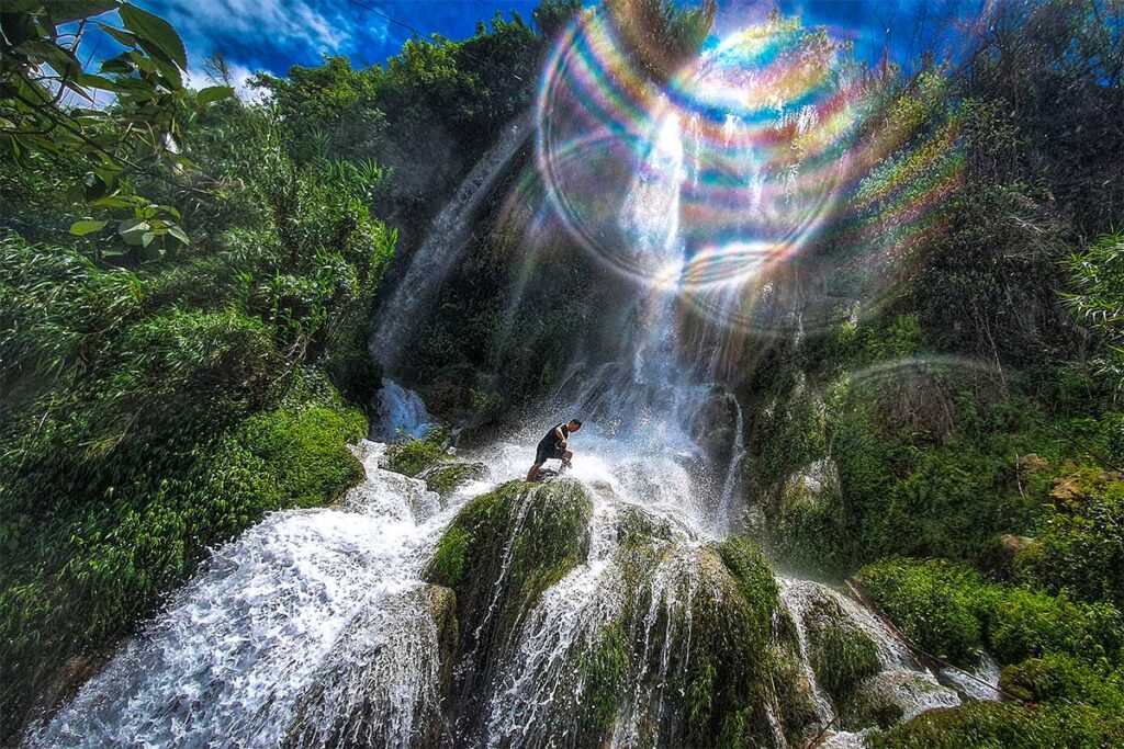 Water dropping down from height and a man standing in the Quang Trung Waterfall in Cao Bang