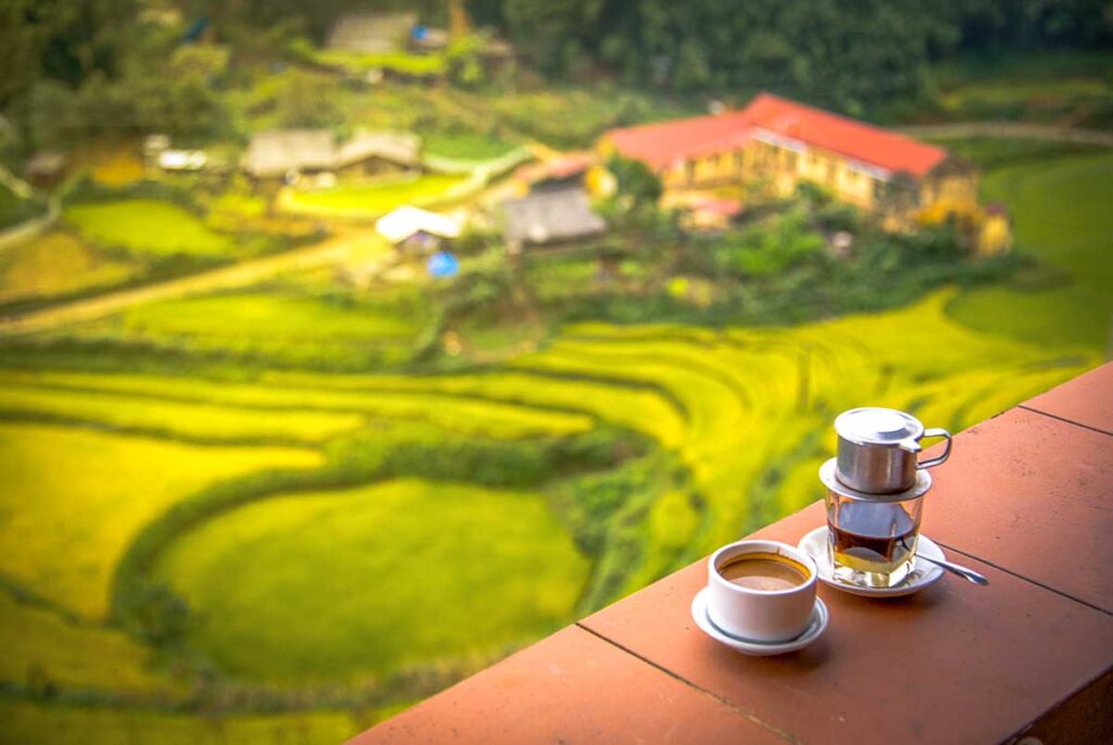 A Vietnamese coffee cup with phin filter standing on a table at a coffee shop in Sapa with amazing views over the rice fields