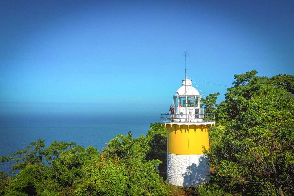 The Tien Sa Lighthouse nestled among trees on Son Tra Peninsula, with the ocean in the background.
