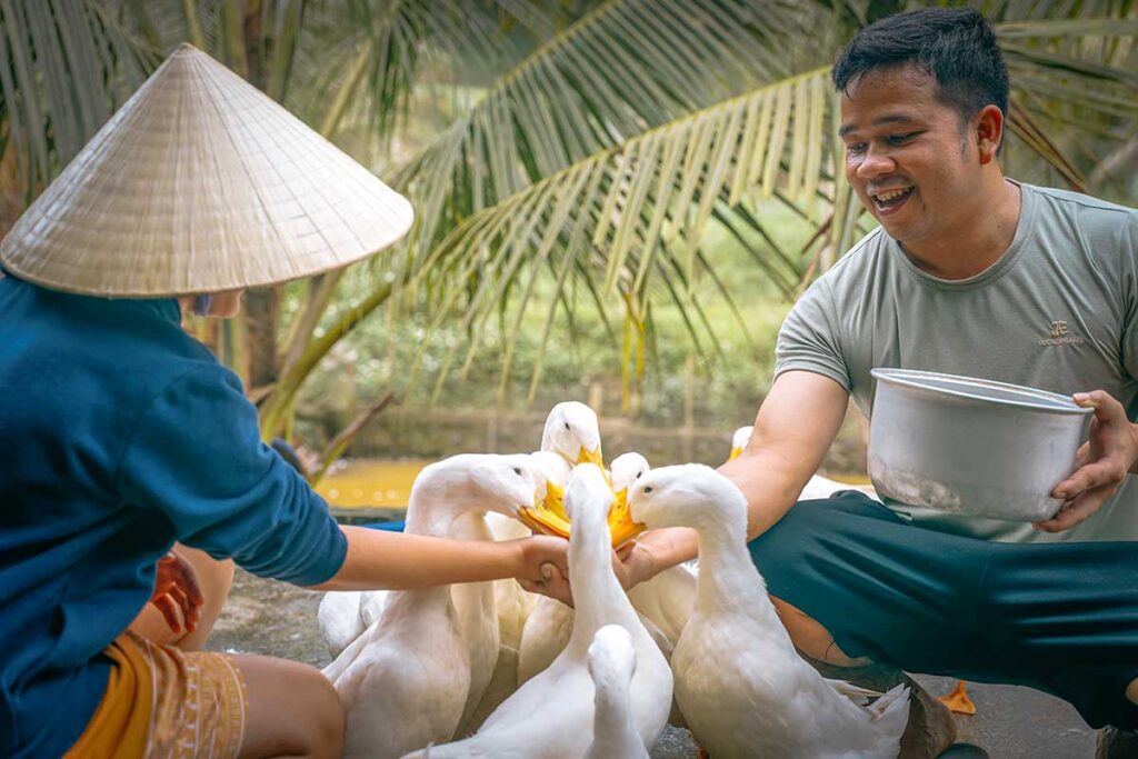 A man and woman feeding ducks at The Duck Stop in Phong Nha