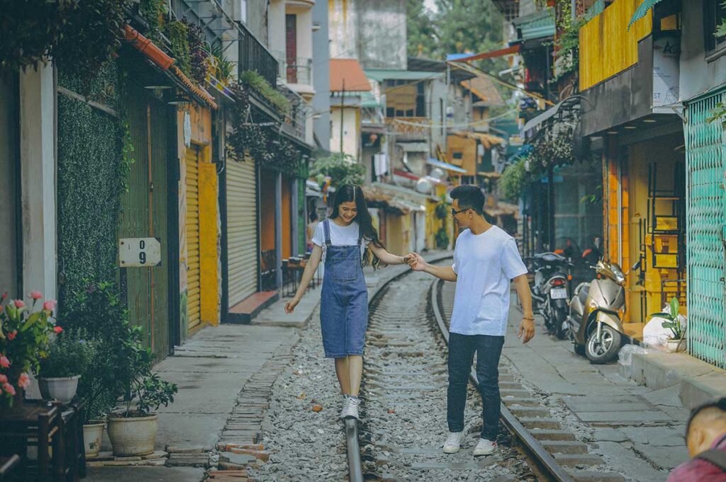 Couple walking hand in hand along Hanoi Train Street, a unique and romantic spot in Vietnam.