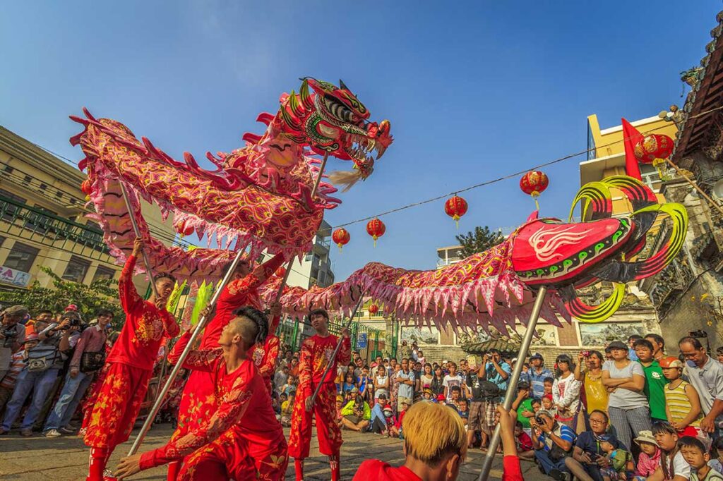 Vietnamese dragon dance with performers in coordinated red costumes, staged in a public square or school courtyard during a cultural celebration.