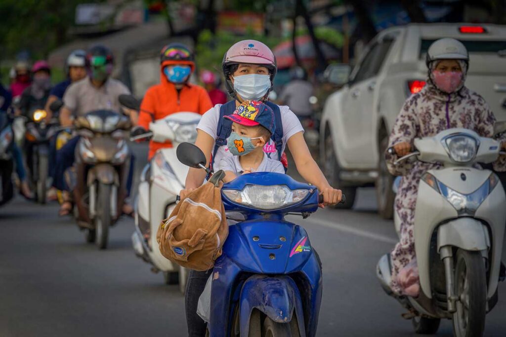 local family riding a motorbike in Vietnam with face masks to reduce exposure to traffic pollution