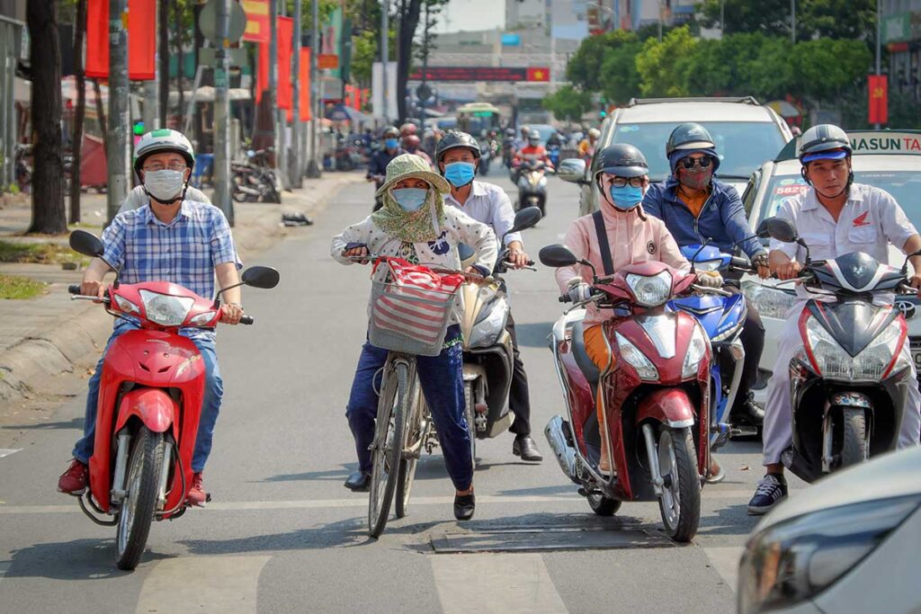 motorbike riders in Vietnam wearing face masks to protect from dust and air pollution in busy city traffic