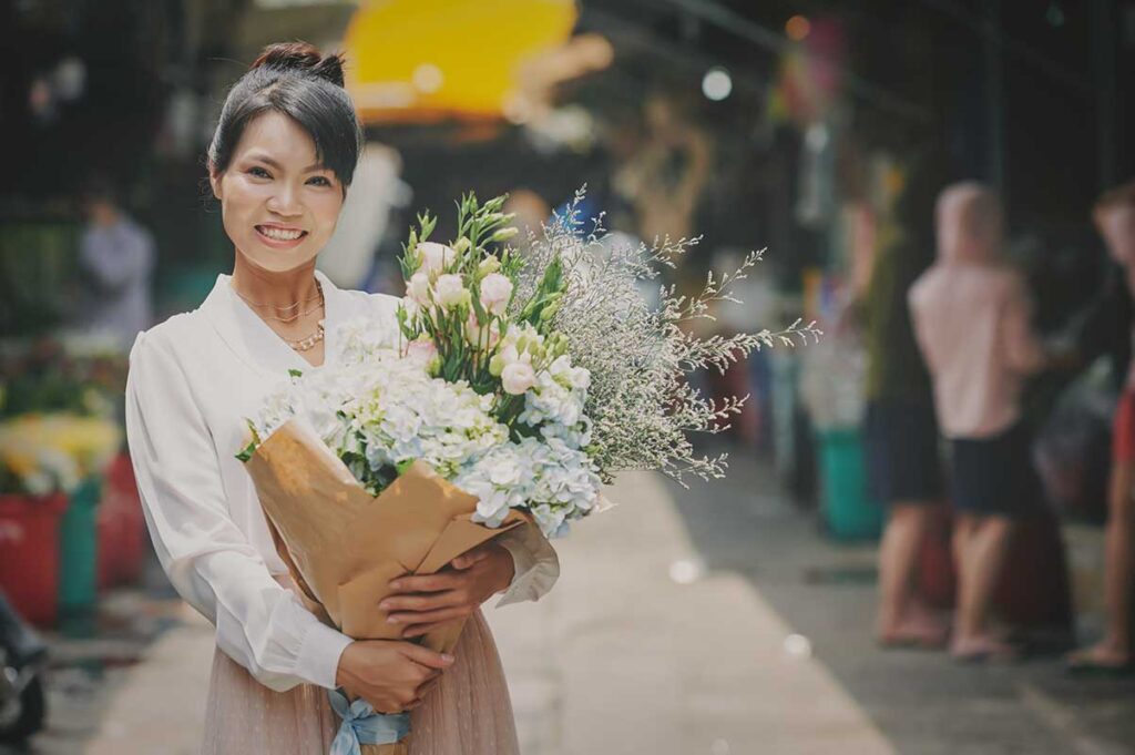 Vietnamese woman holding a bouquet of flowers, reflecting traditional Vietnamese Women’s Day customs.